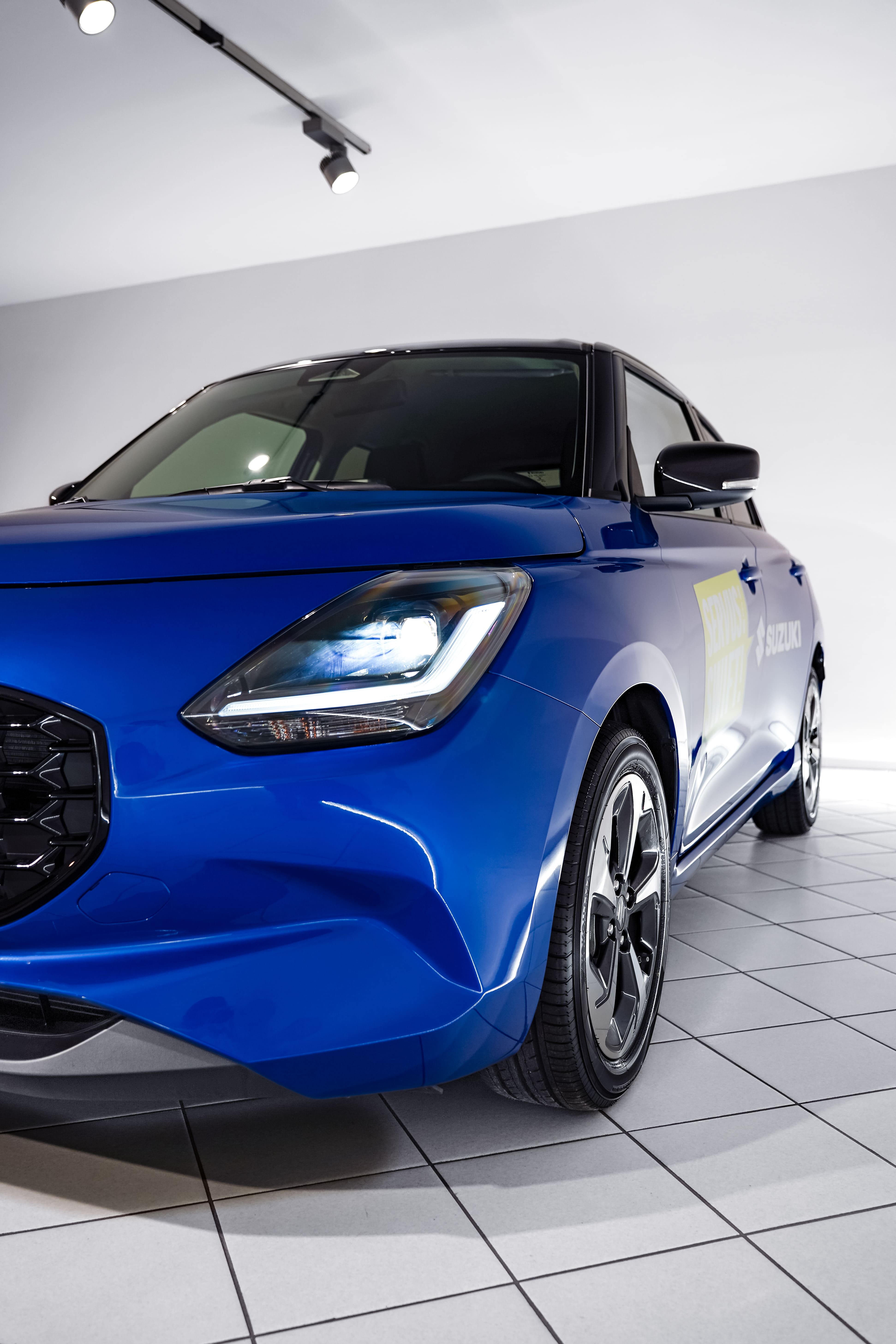 Suzuki Swift in Blau vor weißer Wand